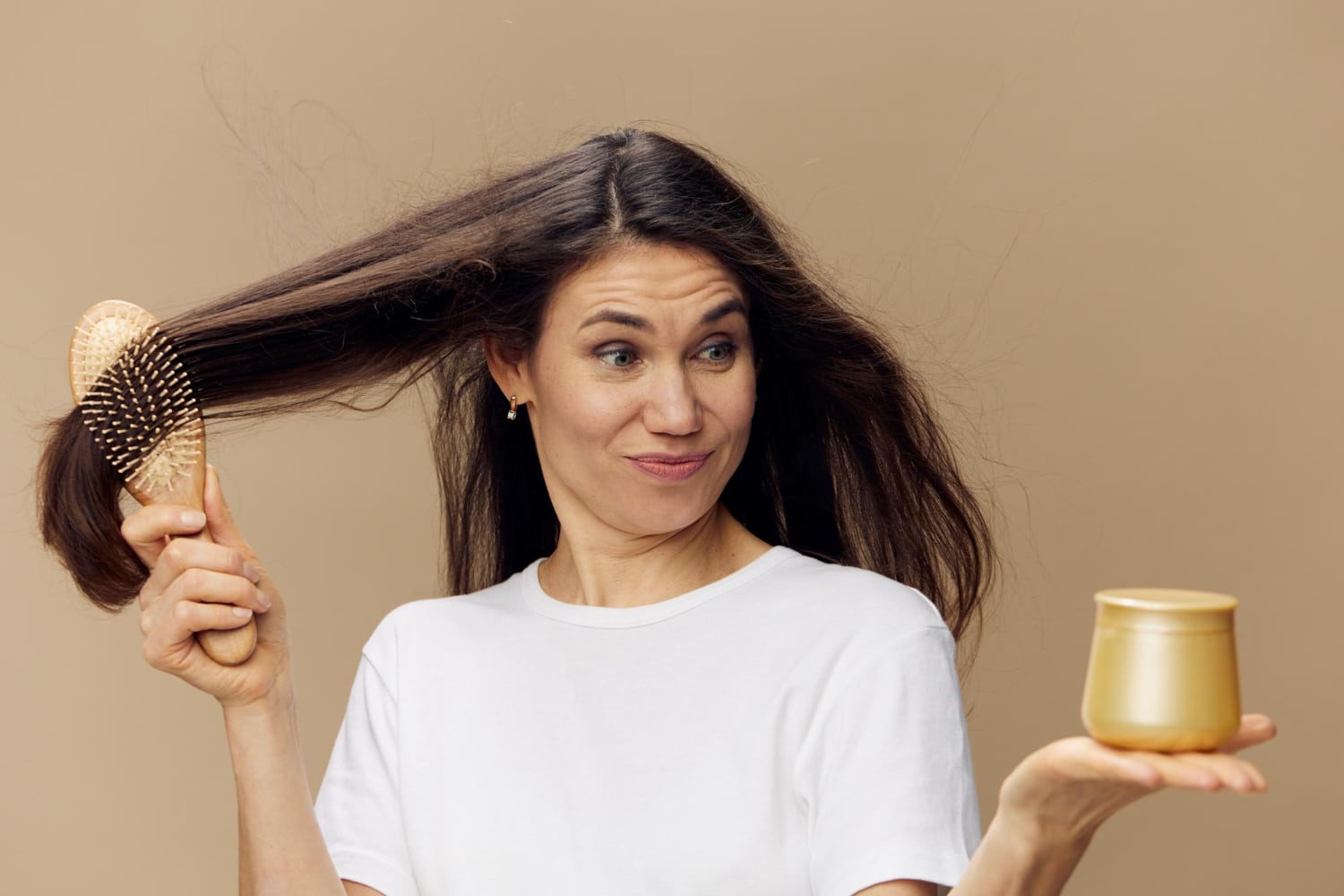 Une femme se brosse les cheveux en regardant un pot de miel, qui améliore la santé des cheveux