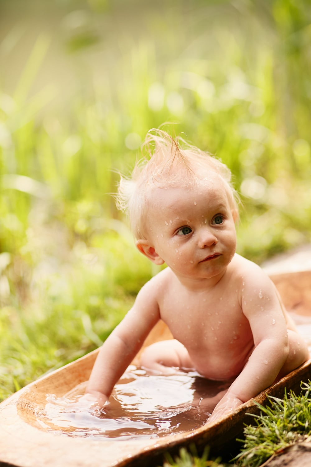 Bébé jouant dans l’eau en plein air, illustrant l’importance de préserver la peau sensible des nourrissons