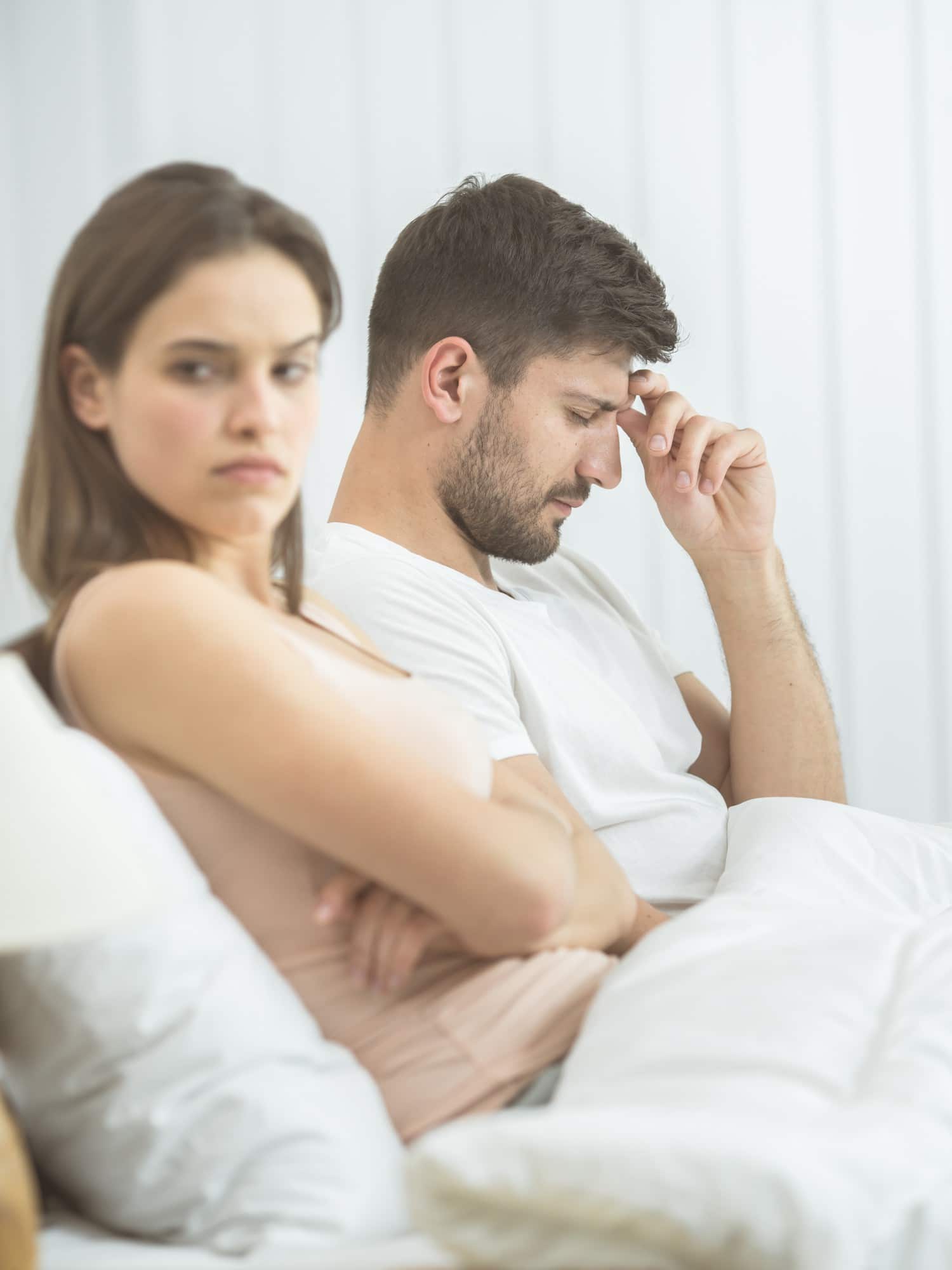 ouple assis dans son lit, chacun plongé dans ses pensées, illustrant les effets du stress, de la fatigue ou des difficultés relationnelles sur la libido.