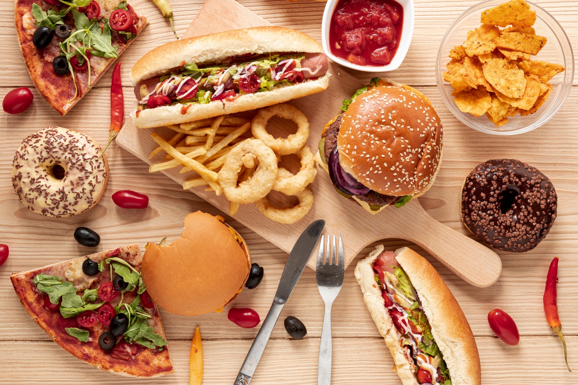 Assortiment de hamburgers, pizzas, frites et aliments ultra-transformés illustrant une alimentation déséquilibrée pouvant favoriser un terrain inflammatoire.