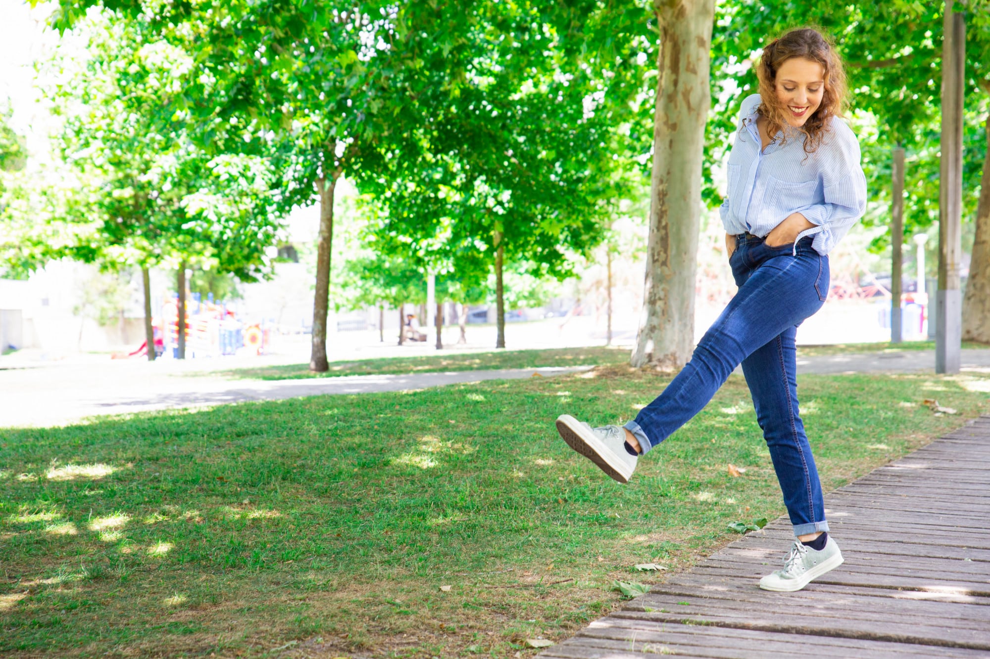 Femme marchant dans un parc et effectuant un mouvement d'étirement, illustrant les bienfaits d'une activité physique douce pour les articulations.