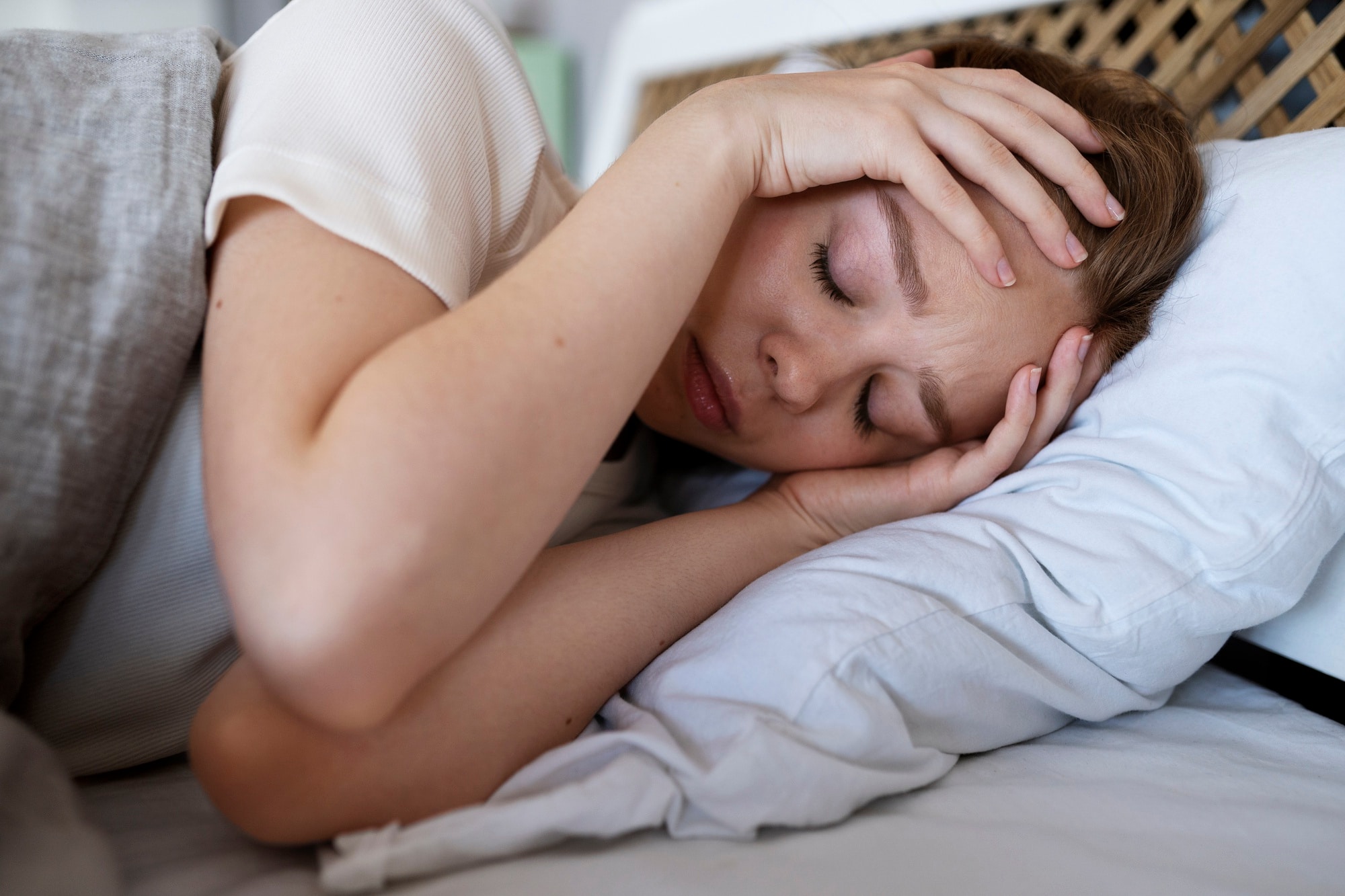Personne allongée, les mains sur le front, illustrant le manque de sommeil et le stress pouvant affecter le confort articulaire.