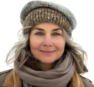 Portrait d’une femme souriante en hiver, bonnet et écharpe, incarnant le cocooning et les soins naturels pour la peau