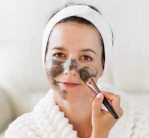 Application d’un masque visage maison au marc de café à l’aide d’un pinceau – soin exfoliant naturel.
