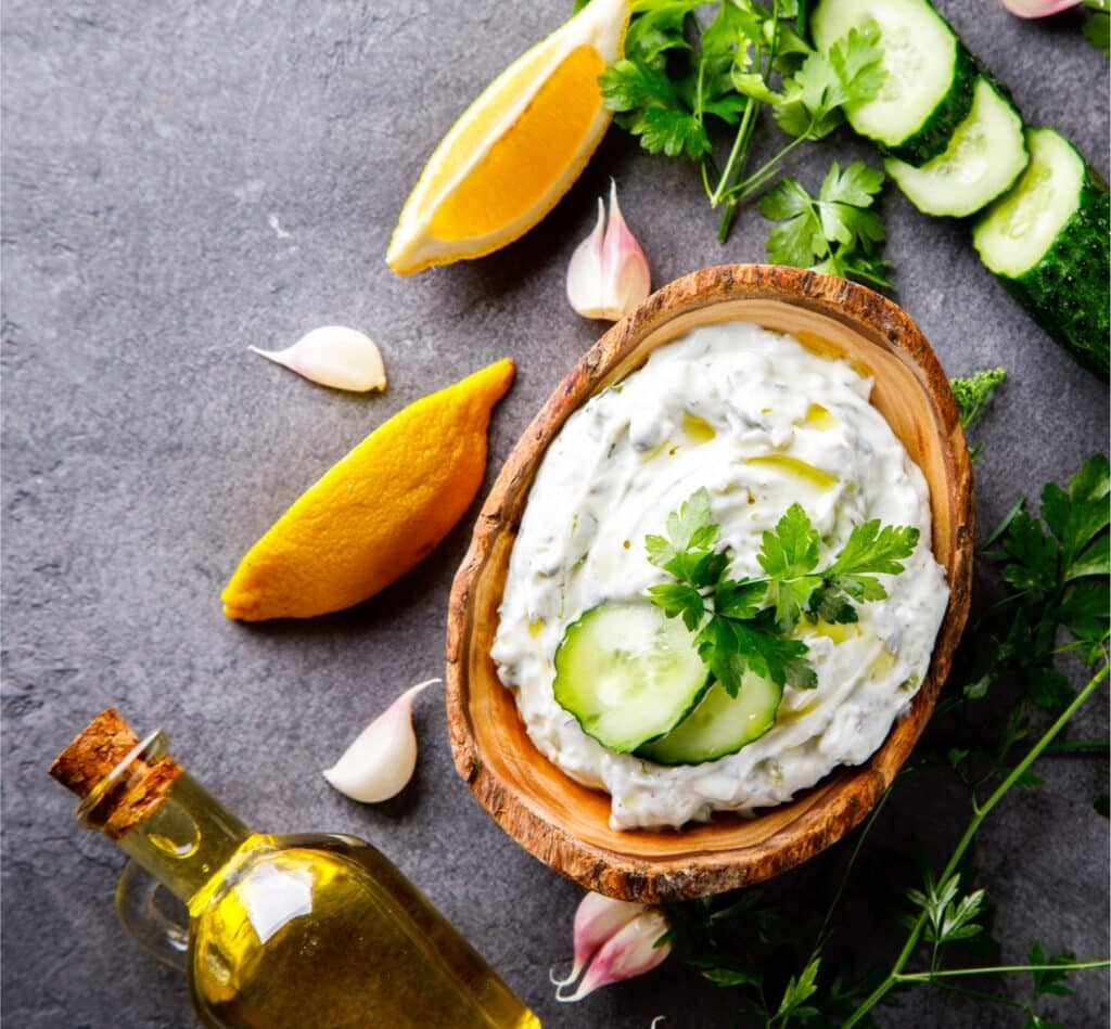 Bol en bois contenant une tartinade crémeuse maison avec citron, huile d’olive, ail et herbes fraîches, ambiance naturelle et saine
