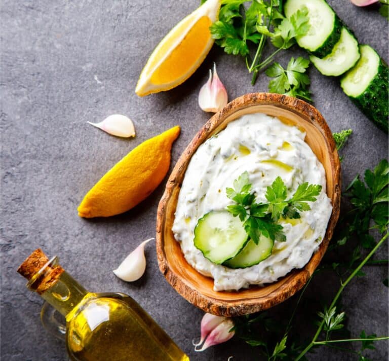Bol en bois contenant une tartinade crémeuse maison avec citron, huile d’olive, ail et herbes fraîches, ambiance naturelle et saine