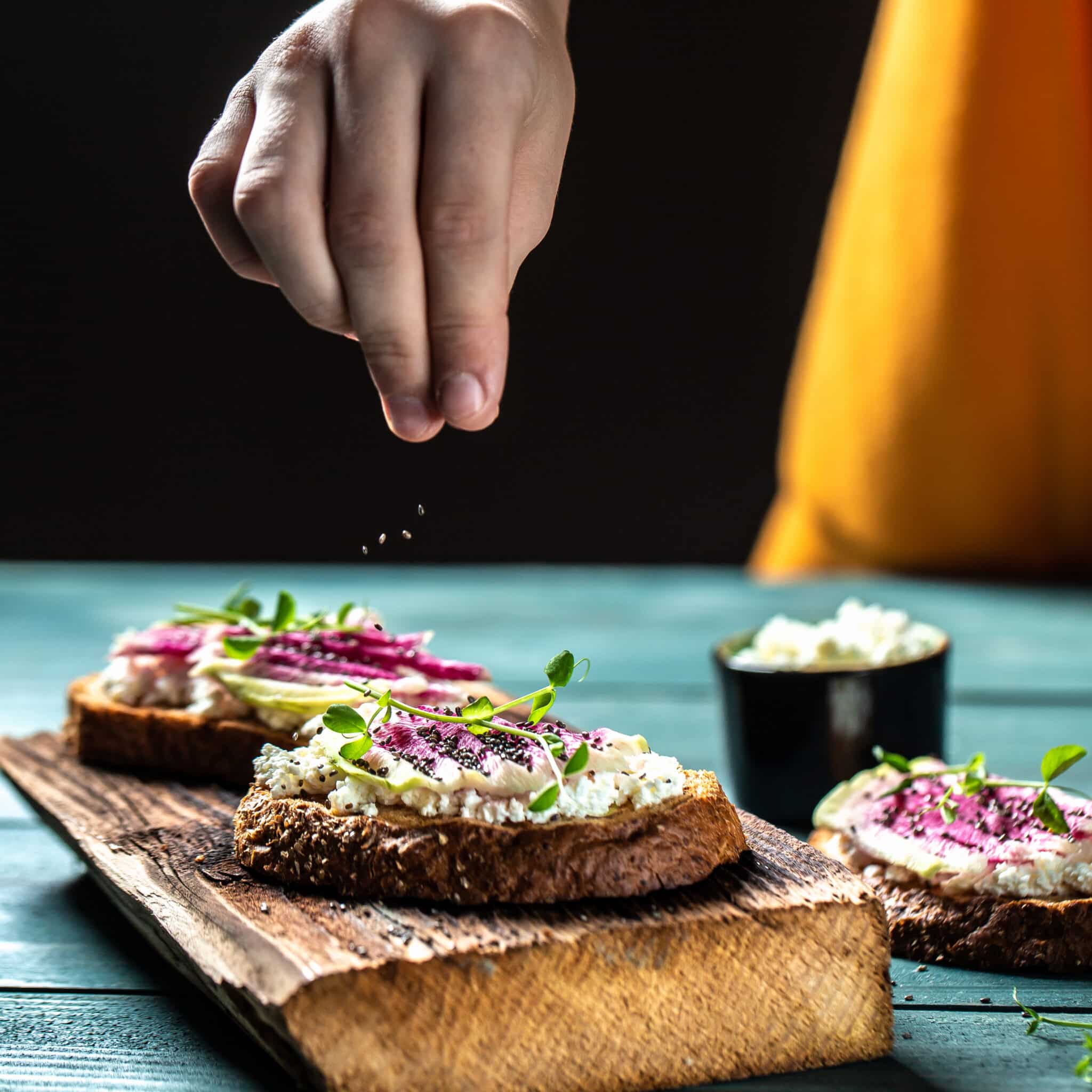 Tartines de pain complet garnies d’une tartinade crémeuse au radis noir et tofu, décorées de radis frais et de micro-pousses, ambiance végétale et gourmande.