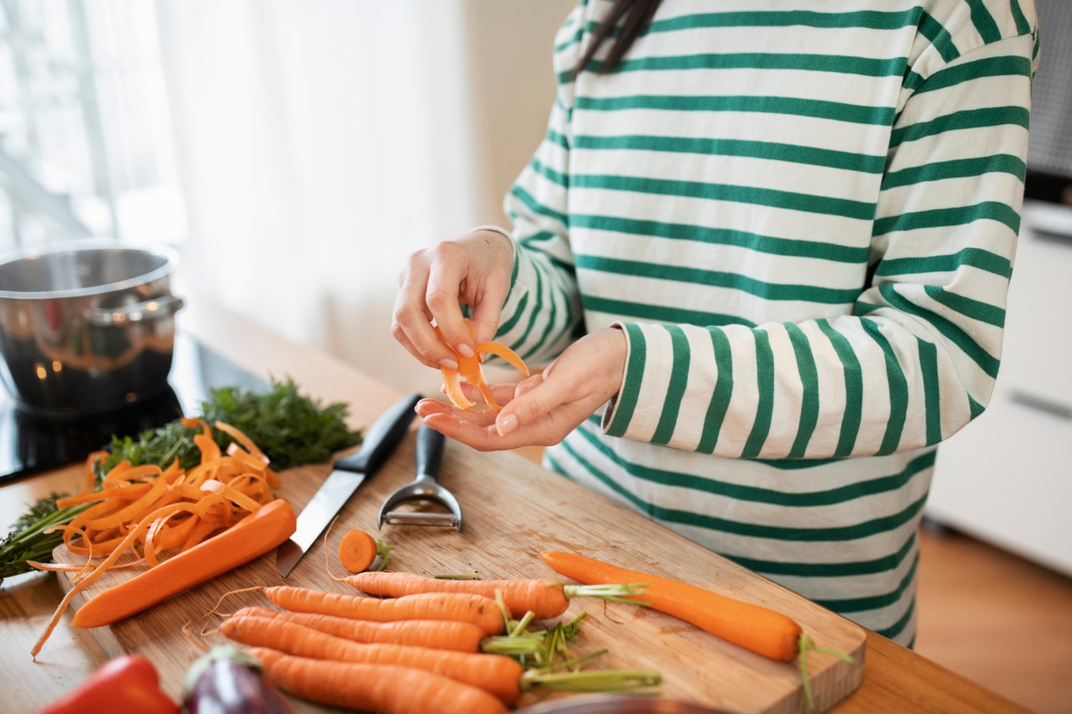 Femme épluchant des carottes en préparation d'un succulent velouté de carottes à l'orange