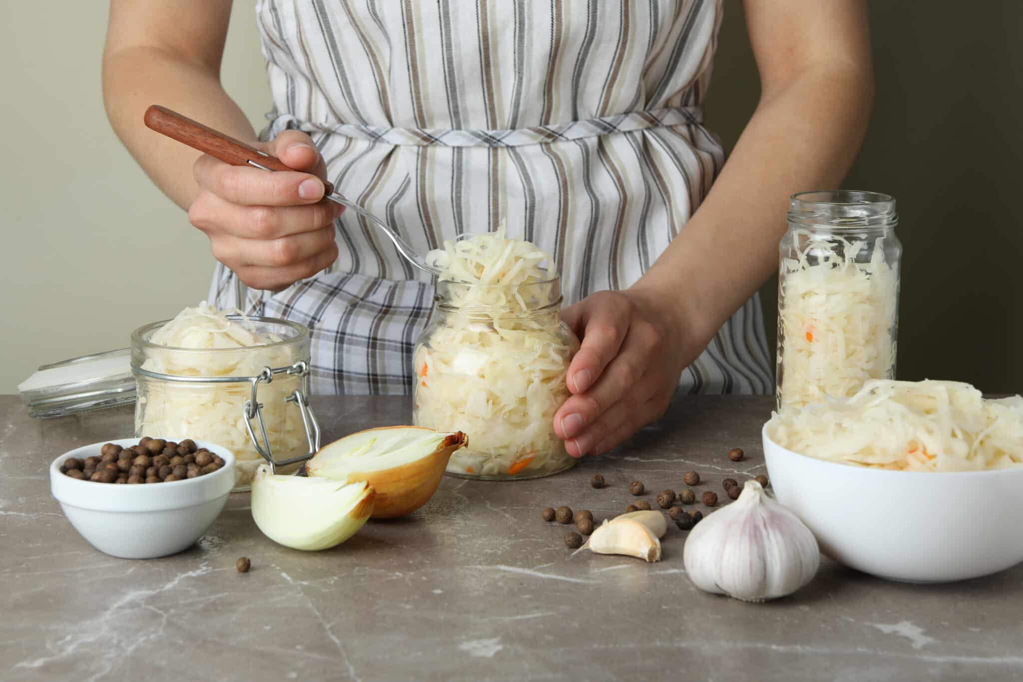 Femme tenant un pot en verre avec de la choucroute crue posée sur une table dans sa cuisine