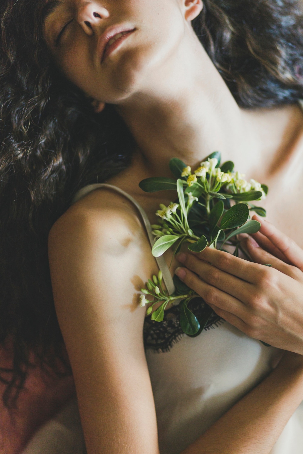 Femme tenant des plantes contre sa poitrine, illustrant une approche douce et consciente du parfum naturel