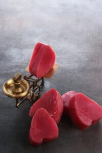 Morceaux de thon crus, montrant des couleurs influencées par l’alimentation ou les pratiques industrielles