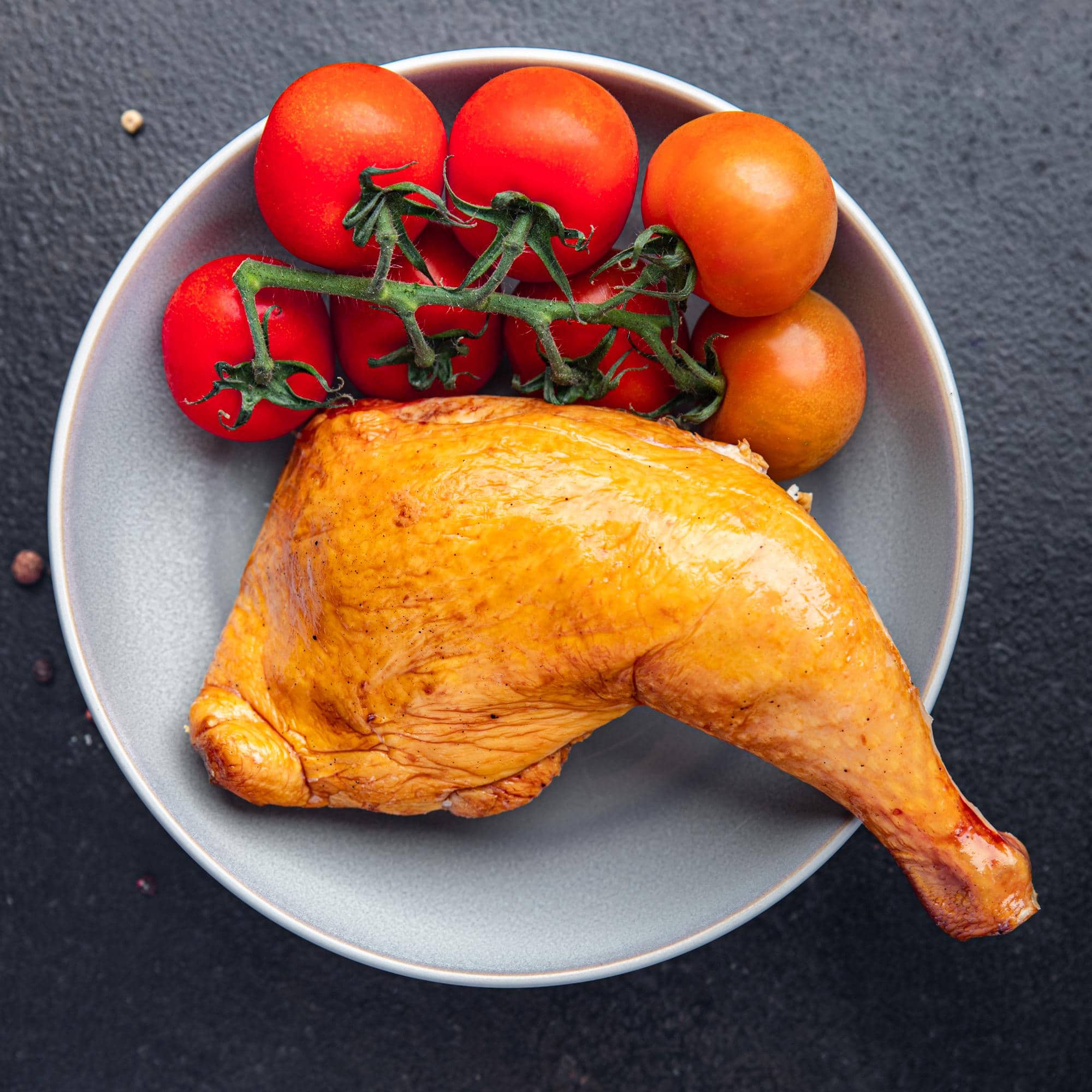 Cuisse de poulet accompagnée de tomates, illustrant l’influence de l’alimentation sur la couleur de la viande