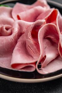 Tranches de jambon rose, illustrant l’usage d’additifs pour maintenir la couleur de la viande