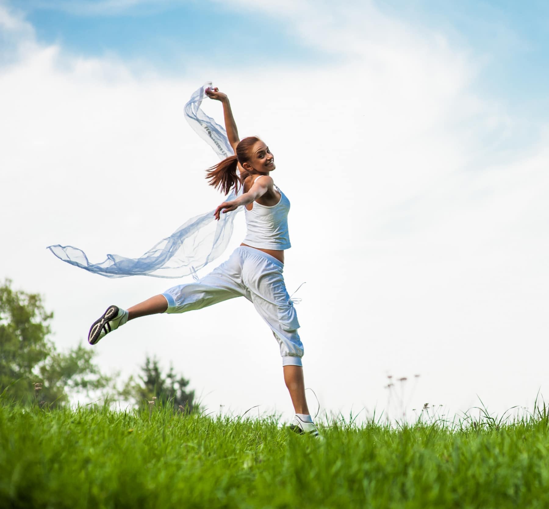 Femme sautant dans l’herbe au printemps symbolisant l’énergie retrouvée et la vitalité naturelle