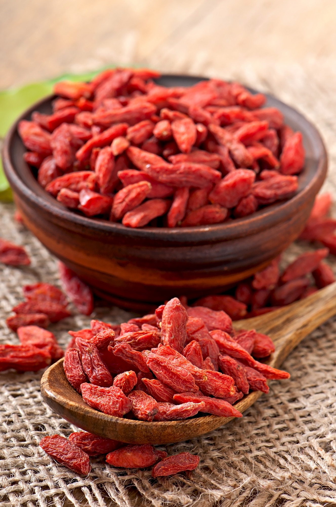 Baies de goji bio séchées présentées dans un bol en bois et une cuillère, riches en antioxydants et idéales pour les petits-déjeuners et encas naturels