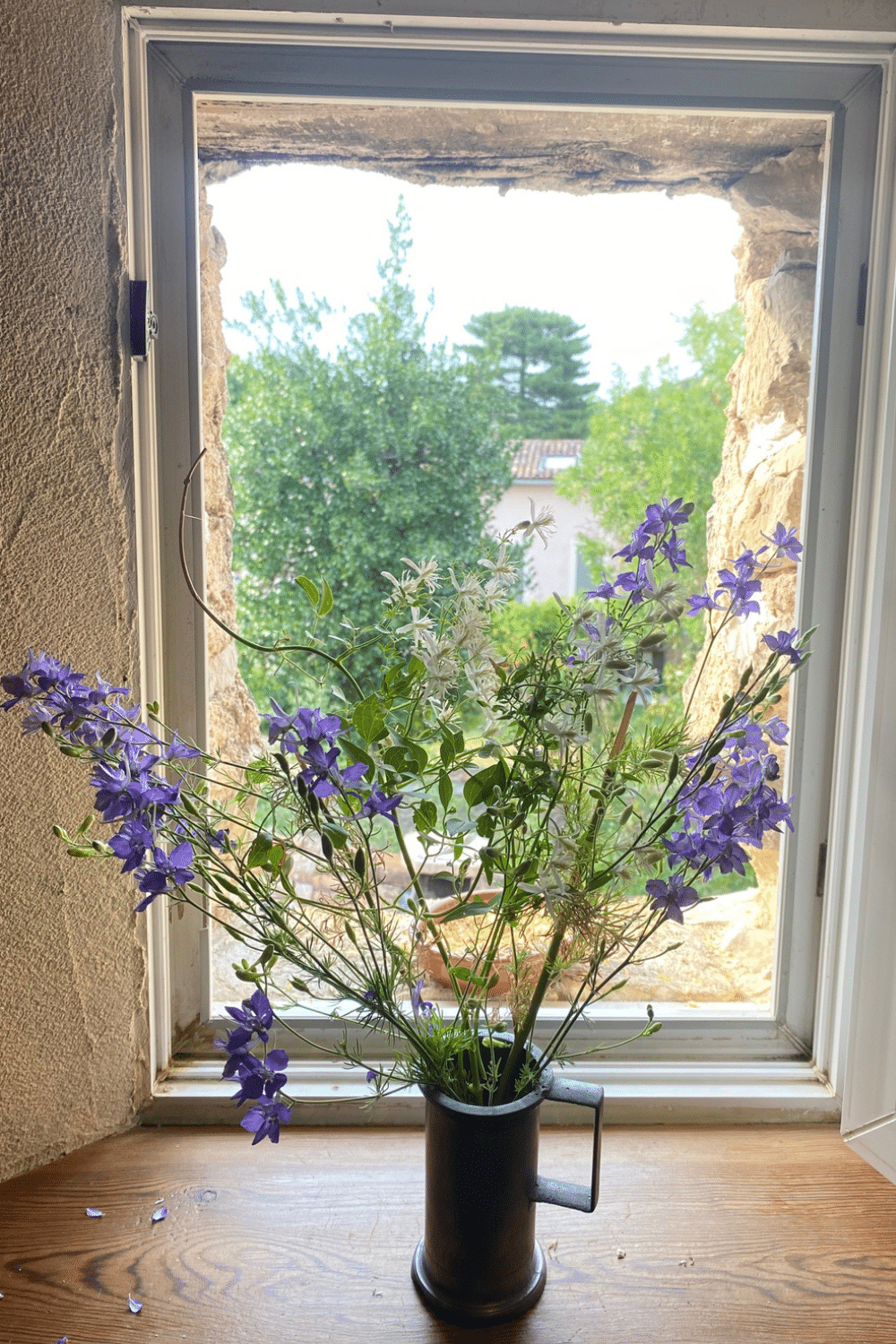 Bouquet de fleurs sauvages composé de clématite des haies et de fleurs des champs, installé devant une fenêtre après une promenade nature.