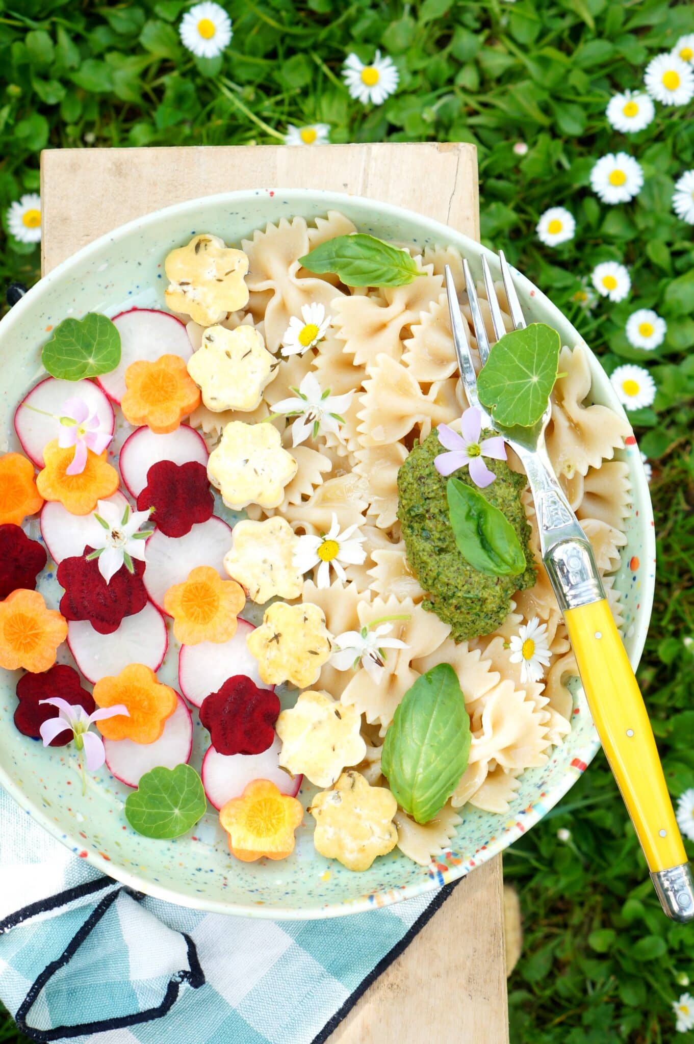 Bowl végétal printanier avec pâtes, pesto vert, légumes découpés en fleurs et fleurs comestibles