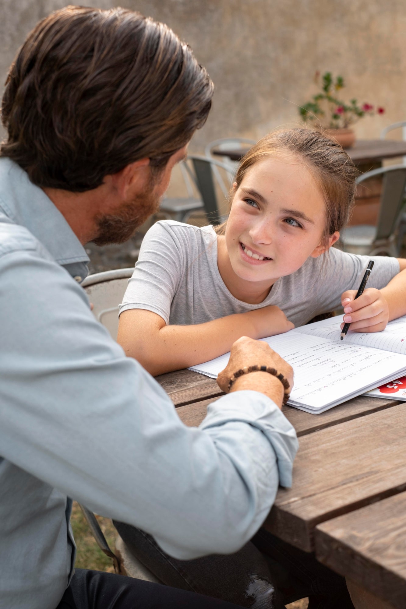 Papa et sa fille écrivant ensemble un message ou une lettre pour partager un moment de complicité.