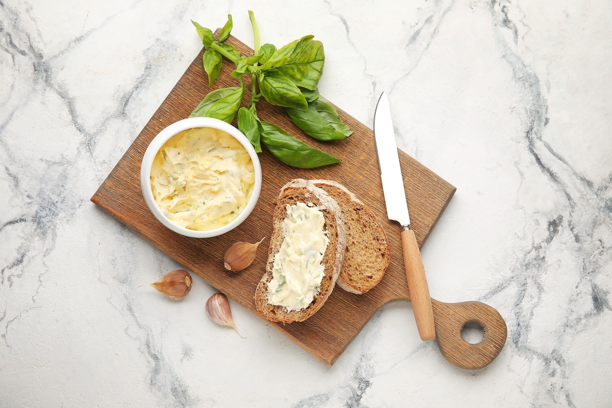 Sauce mayonnaise végane aux amandes et basilic servie avec tartines et basilic frais sur planche en bois