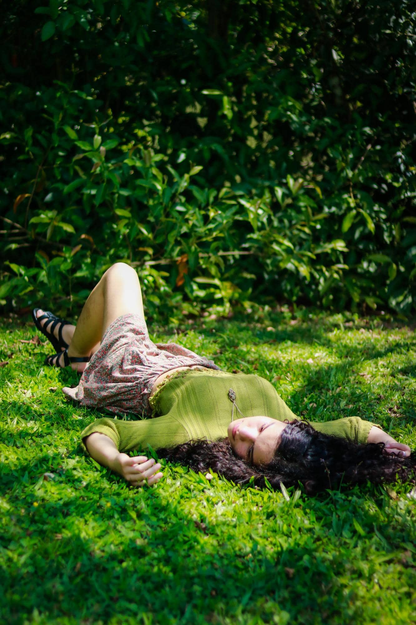 Personne allongée dans l'herbe à l'ombre des arbres profitant d'un moment de repos pendant une journée d'été.