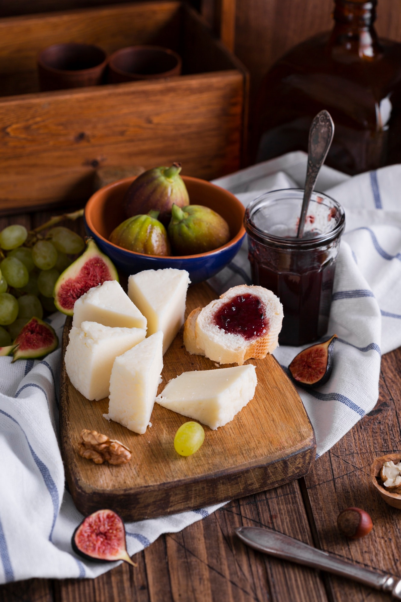 Plateau gourmand composé d'alternatives végétales au fromage accompagné de figues fraîches, raisins, noix et confiture pour un apéritif ou un plateau de dégustation.