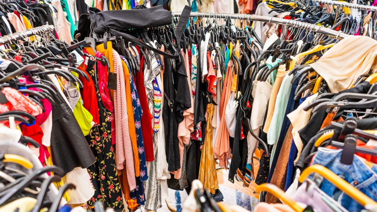Portant rempli de vêtements colorés et entassés, illustrant la surproduction et le gaspillage liés à la fast fashion.