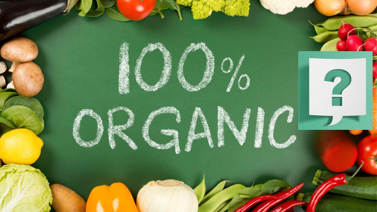 Table garnie de légumes colorés autour de l’inscription “100 % organic”, évoquant la promesse et les défis du tout-bio.