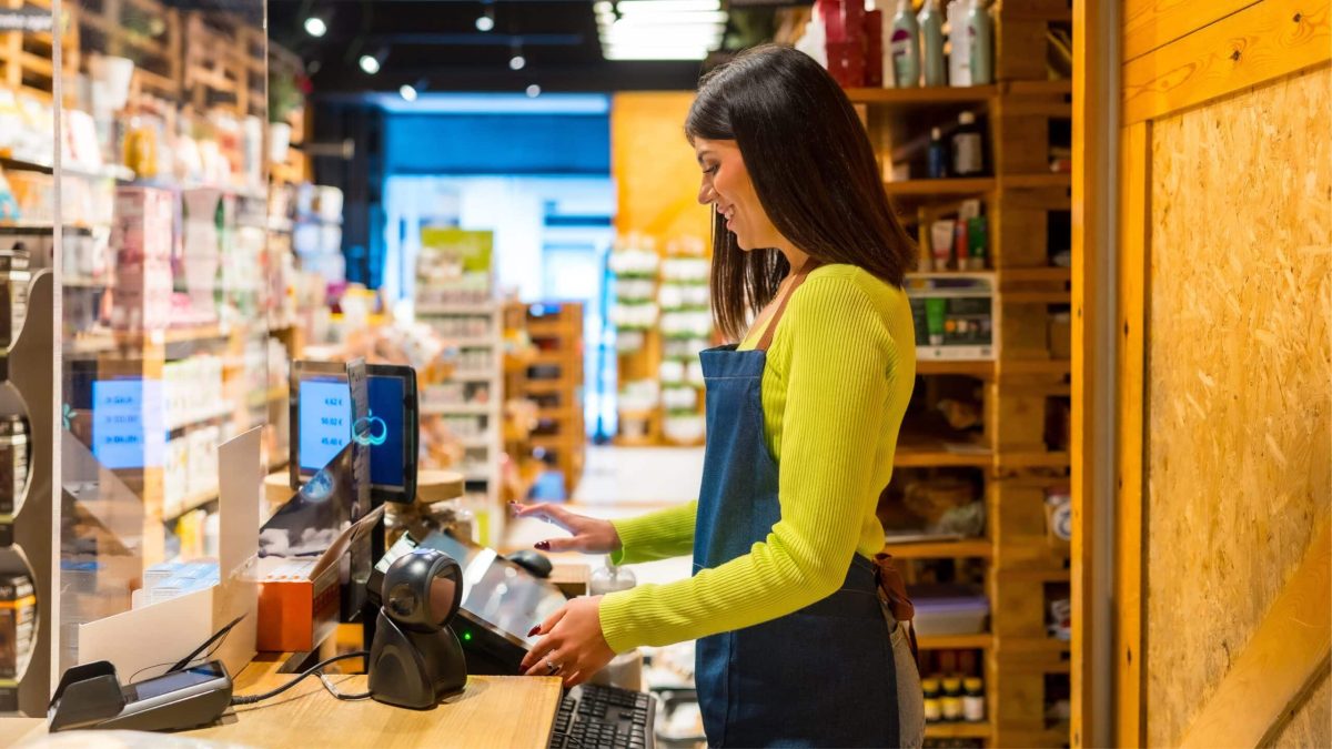 Employée souriante en caisse dans un magasin bio, illustrant la reprise et le dynamisme du secteur après la crise.