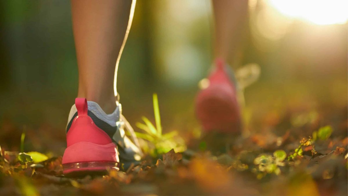 Foulée douce sur un chemin forestier au lever du soleil, symbole d’un running plus écologique et connecté à la nature.