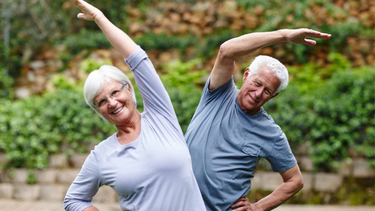 Couple senior pratiquant des exercices de yoga en plein air, souriants et en bonne santé.