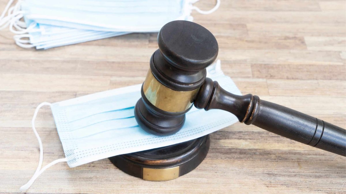 Maillet de juge posé sur un masque chirurgical, symbolisant le frein juridique à la loi anti-fast fashion au niveau européen.
